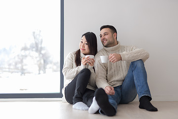 Image showing multiethnic couple enjoying morning coffee by the window