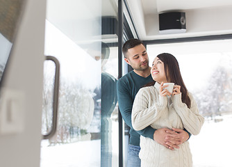 Image showing multiethnic couple enjoying morning coffee by the window