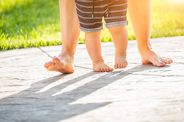 Image showing Mother and Baby Feet Taking Steps Outdoors