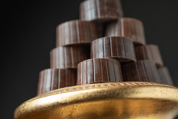 Image showing Stack of Fine Chocolates On Golden Pillar Dish With Dark Backgro