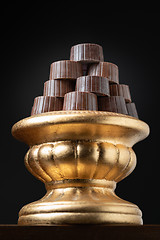 Image showing Stack of Fine Chocolates On Golden Pillar Dish With Dark Backgro