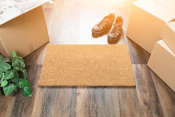 Image showing Blank Welcome Mat, Moving Boxes, Shoes and Plant on Hard Wood Fl