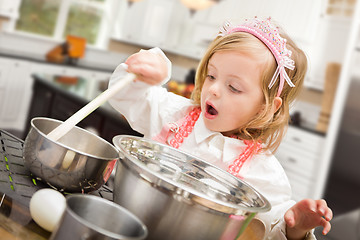 Image showing Cute Baby Girl Playing Cook With Pots and Pans In Kitchen