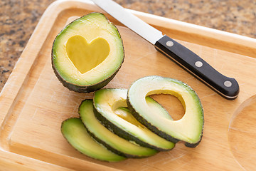 Image showing Fresh Cut Avocado With Heart Shaped Pit Area On Wooden Cutting B