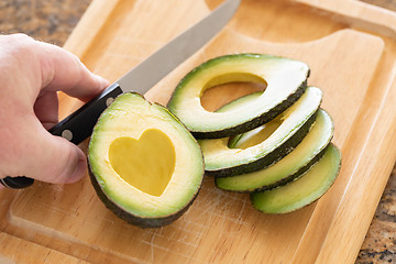 Image showing Male Hand Prepares Fresh Cut Avocado With Heart Shaped Pit Area 
