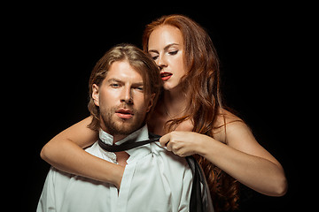 Image showing Real passion. Beautiful young loving couple bonding to each other while both standing against black studio walls