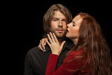 Image showing Real passion. Beautiful young loving couple bonding to each other while both standing against black studio walls