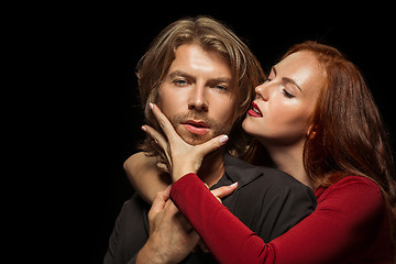 Image showing Real passion. Beautiful young loving couple bonding to each other while both standing against black studio walls