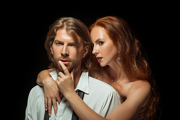 Image showing Real passion. Beautiful young loving couple bonding to each other while both standing against black studio walls