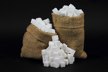 Image showing Cubes Sugar in burlap bags over black. 