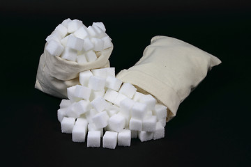 Image showing Spilled Cubes Sugar from bags over black. 