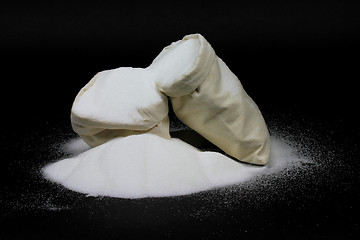 Image showing Spill Natural Granulated Sugar from bags on black 