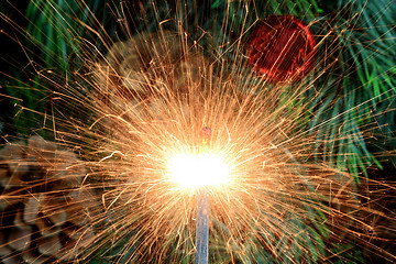 Image showing Burning (lit) sparkler in front of Christmas tree. 