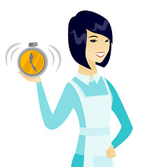 Image showing Young asian cleaner holding alarm clock.