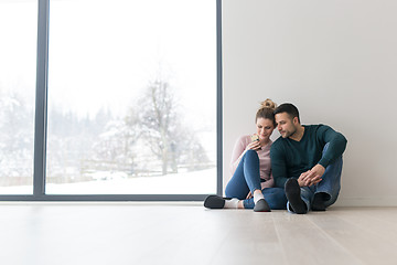 Image showing young couple sitting on the floor near window at home