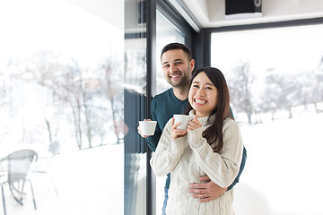 Image showing multiethnic couple enjoying morning coffee by the window