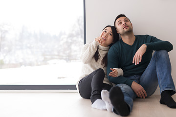 Image showing multiethnic couple sitting on the floor near window at home