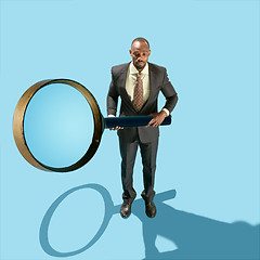 Image showing The conceptual image of business man holding magnifying glass on blue background