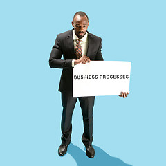 Image showing Businessman holding a white poster with word business processes