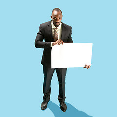 Image showing Business man holding a blank banner isolated on blue background