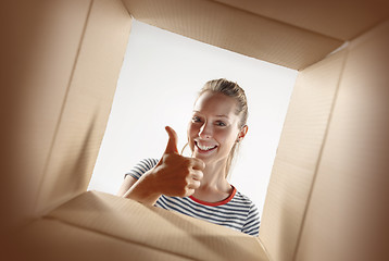 Image showing Woman unpacking and opening carton box and looking inside