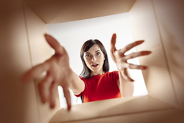 Image showing Woman unpacking and opening carton box and looking inside