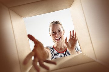 Image showing Woman unpacking and opening carton box and looking inside