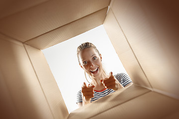 Image showing Woman unpacking and opening carton box and looking inside