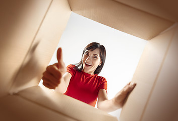 Image showing Woman unpacking and opening carton box and looking inside