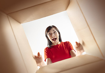 Image showing Woman unpacking and opening carton box and looking inside