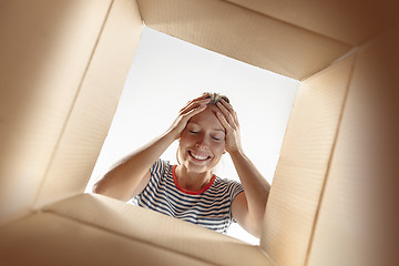 Image showing Woman unpacking and opening carton box and looking inside