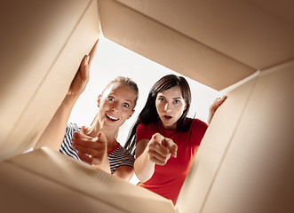 Image showing Women unpacking and opening carton box and looking inside