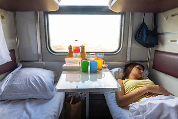 Image showing Interior of a reserved seat train car, a girl sleeps on the lower shelf