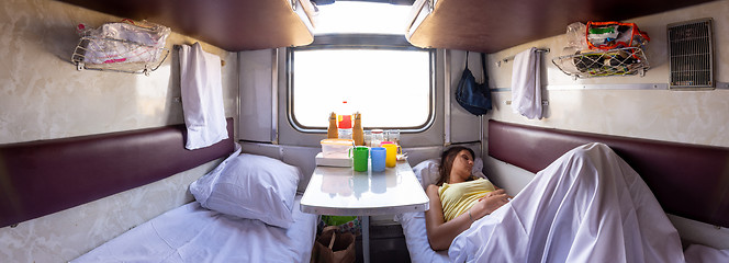 Image showing Panorama of the interior of a reserved seat train car, a girl sleeping on one of the lower shelves