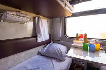 Image showing Empty bottom bunk in a reserved seat carriage and table with dishes