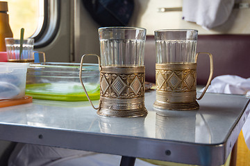 Image showing Empty glasses in metal cup holders stand on a table in a train compartment