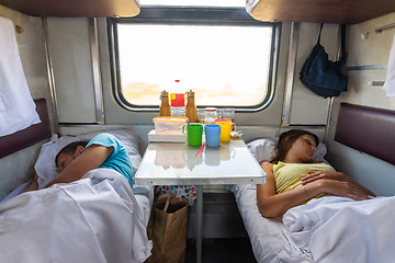 Image showing Man and woman sleep on lower shelves in a train car