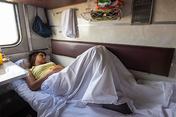 Image showing A young girl sleeps on a lower bunk in a reserved seat of a train car