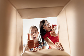 Image showing Women unpacking and opening carton box and looking inside