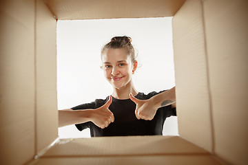 Image showing Woman unpacking and opening carton box and looking inside