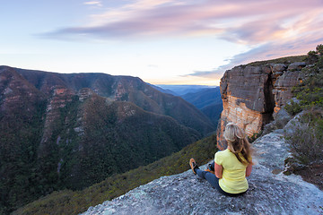 Image showing Woman with wind swept hair sitting  on edge of cliffs