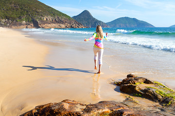 Image showing Woman running along the beach