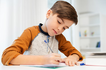 Image showing boy doing homework and writing to notebook at home