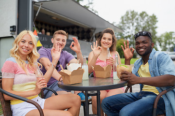 Image showing happy friends with drinks eating at food truck