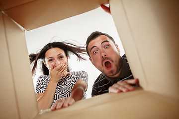 Image showing The couple unpacking and opening carton box and looking inside