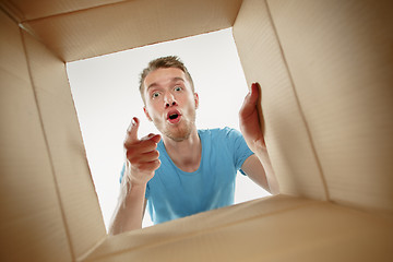 Image showing Man smiling, unpacking and opening carton box and looking inside