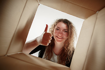 Image showing Woman unpacking and opening carton box and looking inside