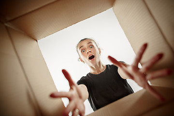 Image showing Woman unpacking and opening carton box and looking inside