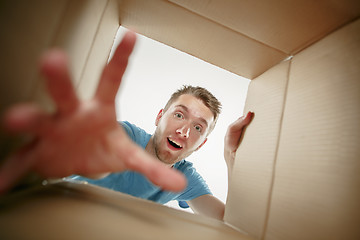 Image showing Man smiling, unpacking and opening carton box and looking inside