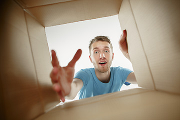 Image showing Man smiling, unpacking and opening carton box and looking inside